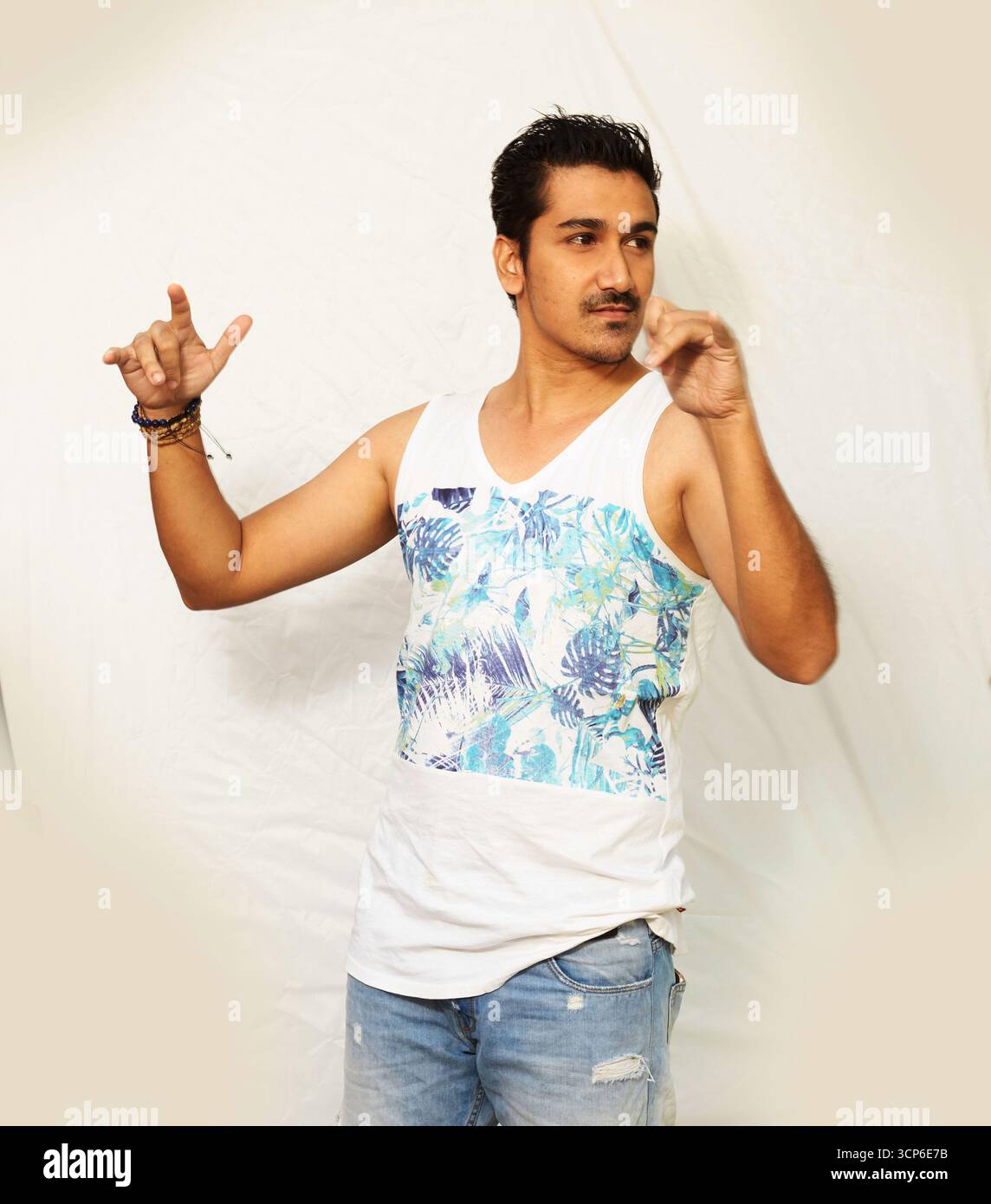 Homme élégant avec un sourire moustachu, posant avec les mains levées Banque D'Images