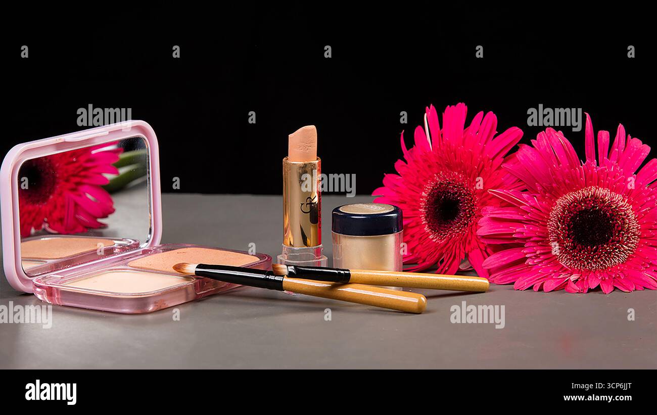 Une nature morte de beauté avec maquillage, pinceaux et fleurs roses vibrantes Banque D'Images