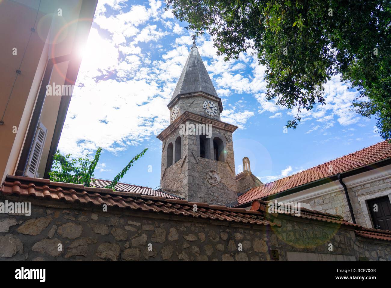 Tour d'église médiévale en pierre avec horloge, toits rouges et ciel bleu à Opatija Croatie . Banque D'Images
