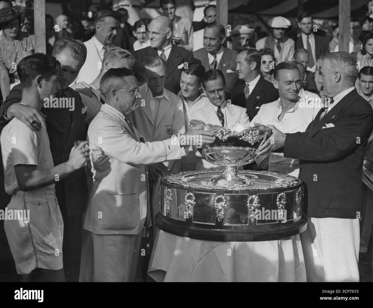 La Coupe Davis reste en Amérique -- Holcombe Ward (à droite), président de l'Association américaine de tennis sur gazon, présente la Coupe Davis, emblème de la suprématie mondiale du tennis, au capitaine Walter Pate (à gauche, coupe des mains sur la coupe) alors que les joueurs des deux équipes regardaient le 5 février après que les joueurs américains ont défendu avec succès le trophée contre les Australiens au Germantown Cricket Club de Philadelphie. Illustré (de gauche à droite). Bobby Riggs, Gene Mako, Capitaine Pate, Joe Hunt (partiellement caché), Jack Bromwich, Schwartz, Adrian Quist, Capitaine Harry Hopman, et Ward. 09 juin 1938. (Photo d'Associated Press photo). Banque D'Images