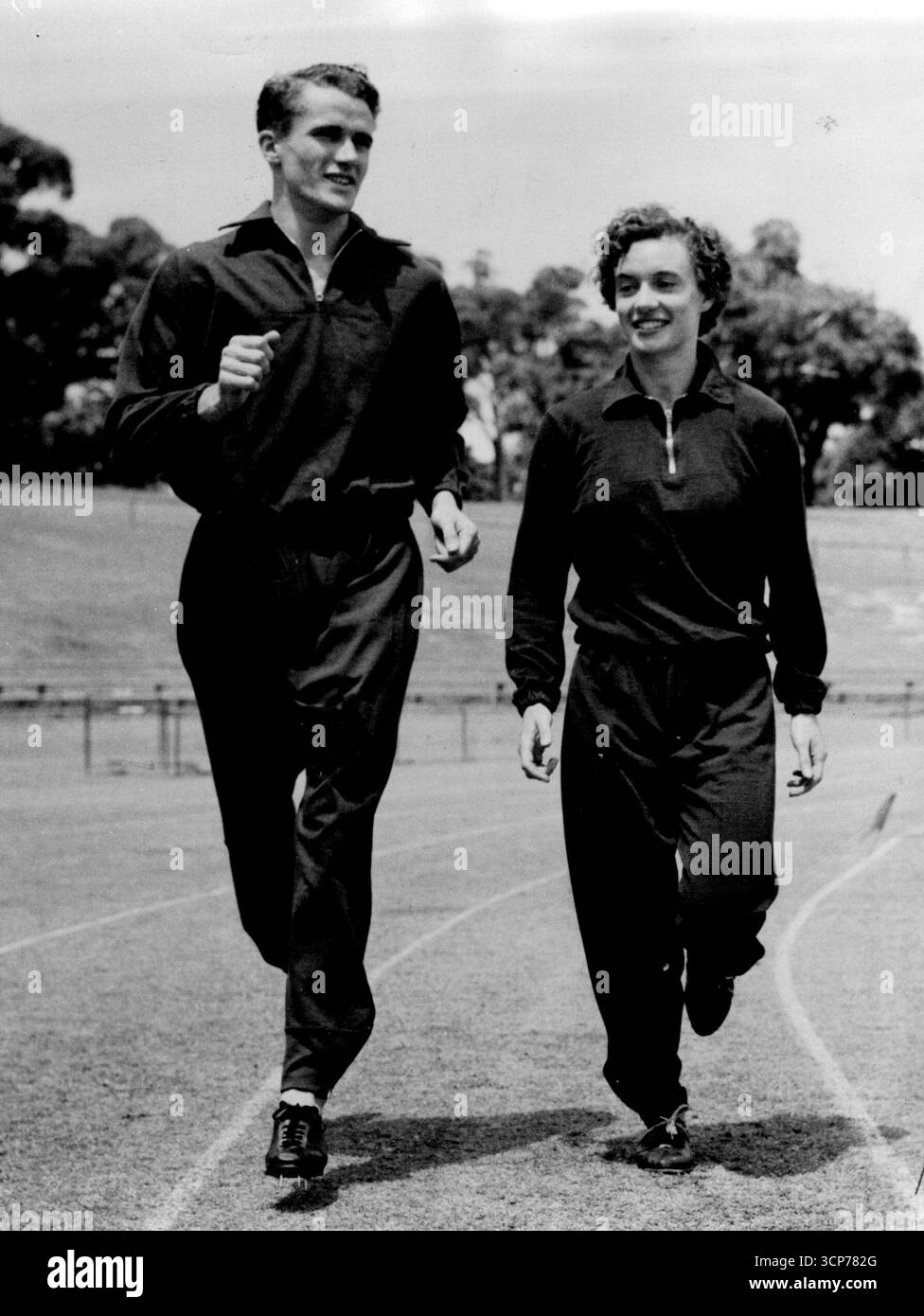 Bill de Gruchy, champion australien de sprint, s'échauffe lors d'une rencontre sportive. Avec lui, la coureuse des Empire Games Verna Johnston -- la première femme à battre la néerlandaise volante Fanny Blankers Koen lors de la visite des champions australiens. 18 juillet 1951. Banque D'Images