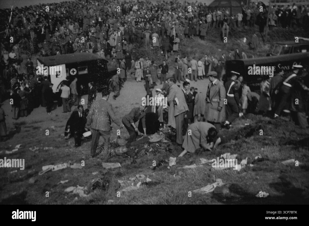Quand la mort de l'air a frappé la colline de Farnborough -- la sombre scène sur la colline où les spectateurs ont été tués et les blessés sont couchés sur le sol pendant que les premiers soins sont donnés. En arrière-plan est une ambulance et une foule qui semble déconcertée et stupéfaite.vingt personnes - le pilote John Derry et un passager et 18 spectateurs ont été tués et 35 spectateurs ont été blessés lorsque le prototype No.1 du chasseur à réaction semi-secret de Haviliand 110 tous temps a explosé au spectacle aérien de Farnborough (Hampshire) ce jour-là (samedi). Les spectateurs étaient sur une colline frappée par un moteur en feu du plan Banque D'Images