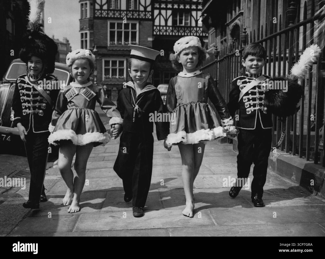 Marcher dehors -- de gauche à droite - Raymond Mathias, 6 : Stacey Gregg, 6 : Richard Parker - Bowles, 4 : Rosemary McGrill, 5 : and the Hon. David Ward, 5.main dans la main avec leur escorte armée-marine, de petits danseurs arrivent en costume pour une répétition à Chelsea, Londres, de la Matinee qui sera donnée le 8 juillet en aide de la Ligue de pitié. 4 juillet 1952. (Photo de Reuterphoto). Banque D'Images