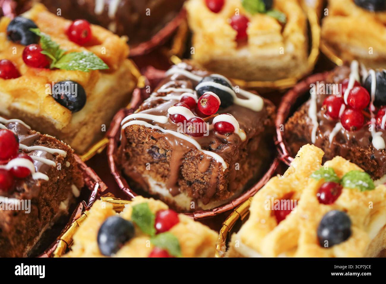 Gâteaux sucrés avec garniture de baies. Viennoiseries décorées de crème et de fruits en gros plan. Assortiment de desserts pour table de fête. Produits de boulangerie maison. Banque D'Images