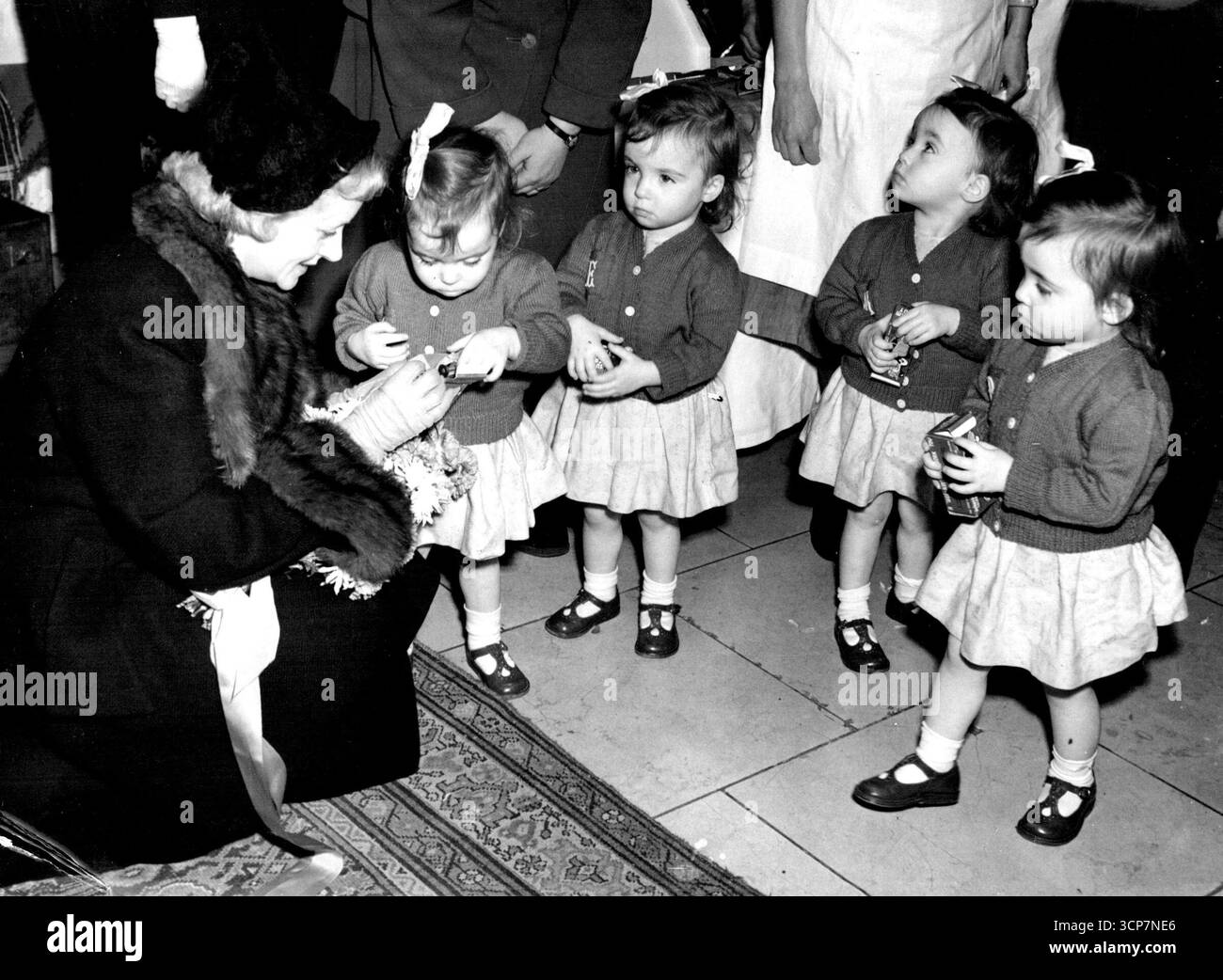 Quads présentent bouquet à Evelyn Laye - Marie, Patricia, Francis et Edna Coles, les Quads de 2 ans 3 mois, présentant un bouquet à Miss Evelyn Laye à l'ouverture des salles d'exposition Red Cross Bazar, Piccadilly aujourd'hui. 3 décembre 1952. Banque D'Images