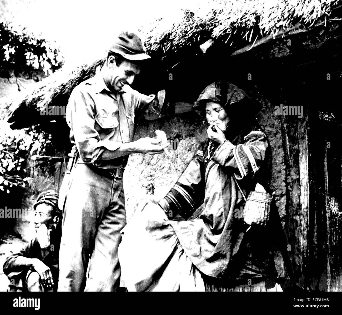 Quelque chose de différent pour la femme Lolo -- le premier lieutenant Charles F. Schwep, photographe de l'armée (No Home Town Given), apprécie le résultat de son don d'une cigarette à une femme Lolo âgée pendant l'expédition de l'armée en Chine occidentale. L'enquête de l'armée rapporte que les aviateurs américains pourraient y être retenus captifs et dit maintenant que la recherche a « prouvé » les histoires fausses. 22 novembre 1947. (Photo de AP Wirephoto). Banque D'Images