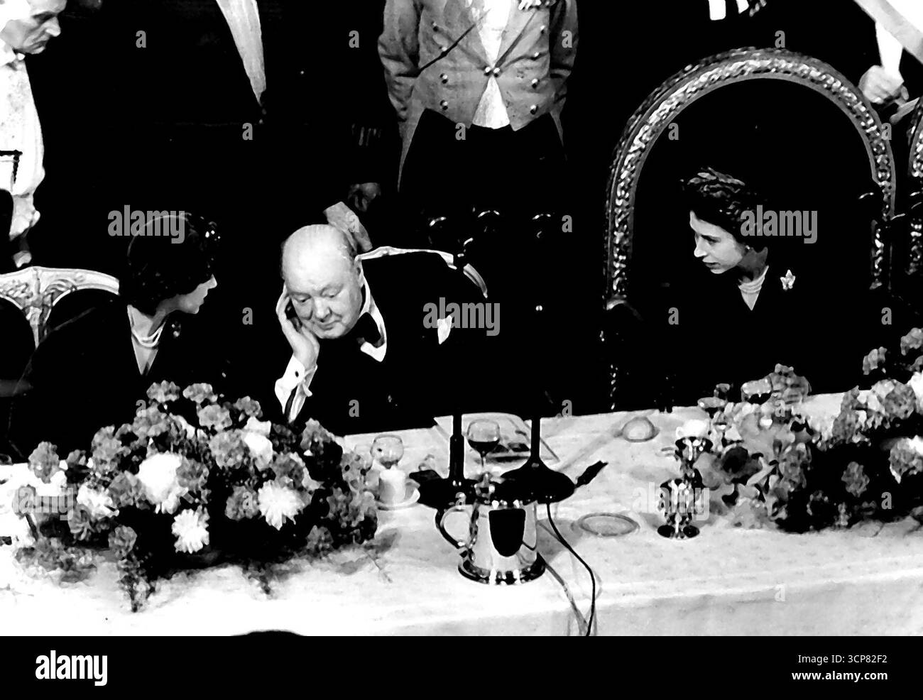 Churchill et la princesse Margaret dans Guildhall Luncheon Chat assis entre les deux princesses, le premier ministre, Mr. Winston Churchill, se penche pour attraper les paroles de la princesse Margaret tandis que les princes Elizabeth écoute de sa position à proximité. L’occasion est le déjeuner Guildhall aujourd’hui (lundi) au cours duquel la princesse Elizabeth et le duc d’Édimbourg ont été officiellement accueillis de retour de leur tournée canadienne par la ville de Londres. La princesse et le duc ont reçu une adresse de bienvenue et la princesse a répondu par un court discours. Le premier ministre a proposé au toast à la princesse Eliz Banque D'Images