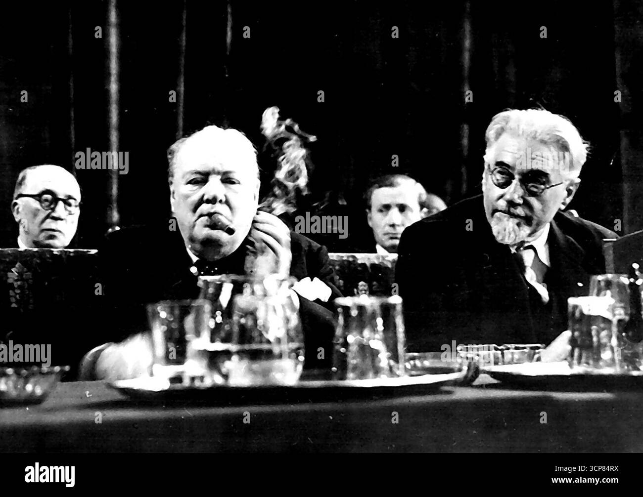 Churchill se concentre sur l'Union européenne inaugure le Congrès de la Haye. La Haye - boucles de fumée du gros cigare de Winston Churchill car, assis derrière une carafe à eau et des verres, il se concentre apparemment sur le discours qu'il devait prononcer lors de la réunion inaugurale du Congrès de l'Europe dans la salle des chevaliers de la capitale néerlandaise avec lui est l'ancien premier ministre socialiste de France, M. Paul Ramadier. Churchill a été vivement acclamé par les délégués de 23 Nations, dont les 16 dans le Plan Marshall - quand il a appelé à la création immédiate d'une Assemblée européenne et a demandé : "Tant de millions o Banque D'Images