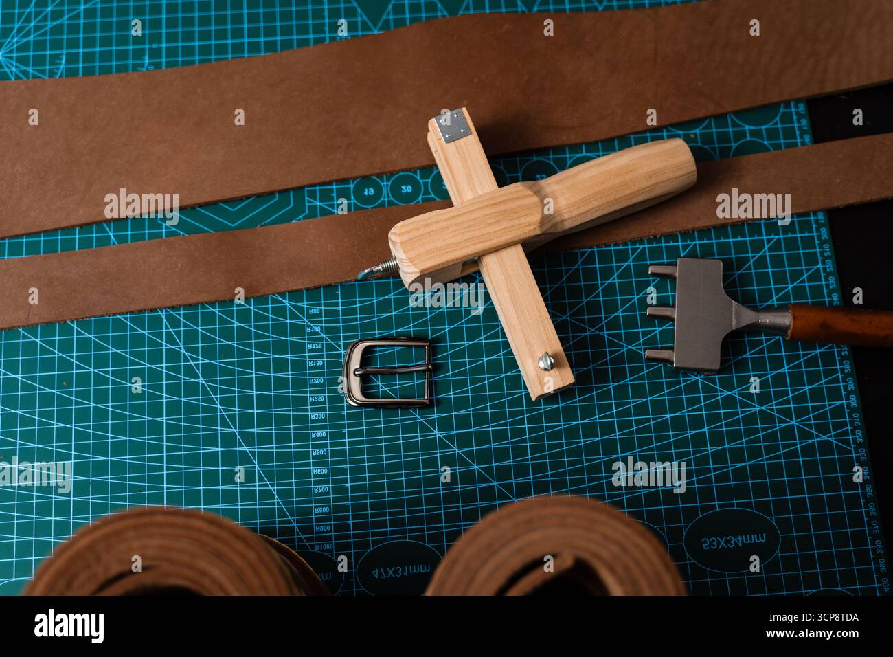 Outils de maroquinerie et préparation pour la fabrication de courroies. Configuration de travail du cuir avec outils, boucle et bandes de cuir disposées soigneusement sur un tapis, prêt pour b Banque D'Images