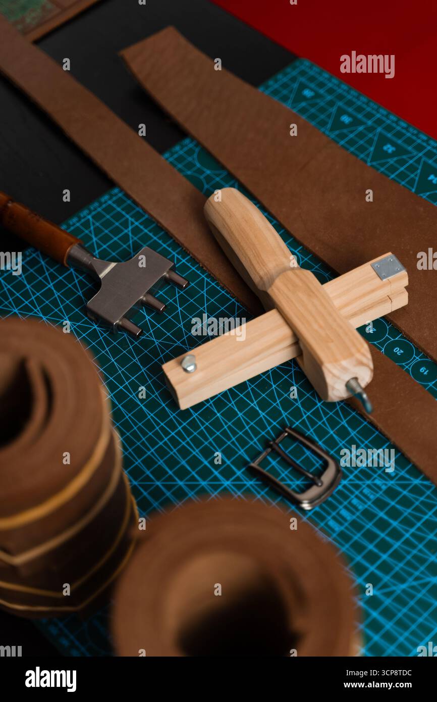Outils de maroquinerie et préparation pour la fabrication de courroies. Configuration de travail du cuir avec outils, boucle et bandes de cuir disposées soigneusement sur un tapis, prêt pour b Banque D'Images