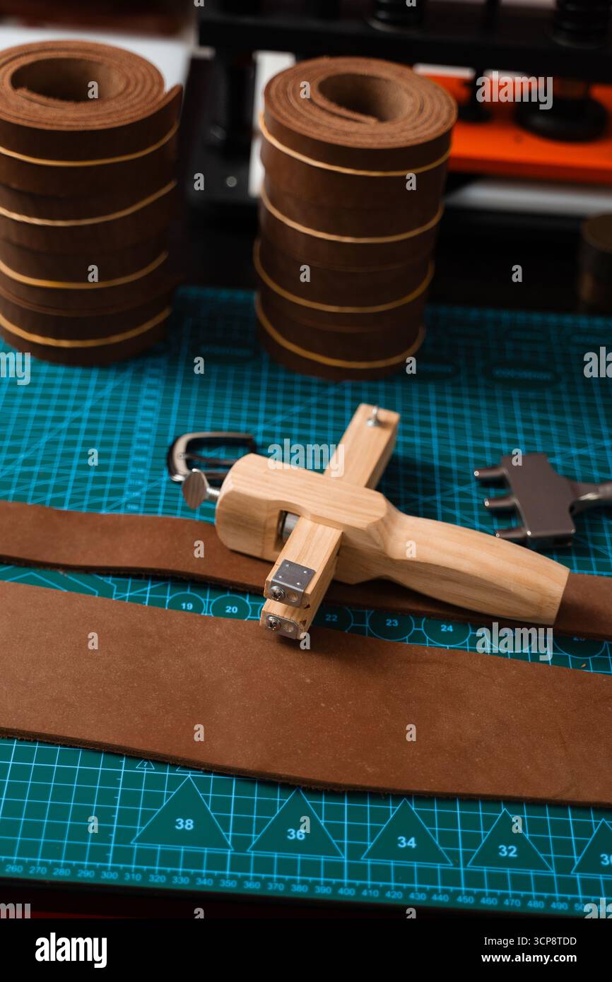 Outils de maroquinerie et préparation pour la fabrication de courroies. Configuration de travail du cuir avec outils, boucle et bandes de cuir disposées soigneusement sur un tapis, prêt pour b Banque D'Images
