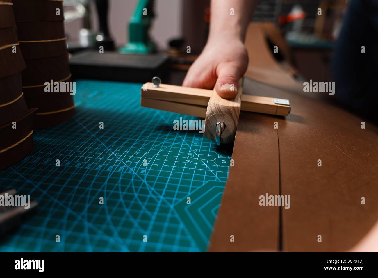 Préparation de ceinture en cuir à la main avec coupe-sangle en bois sur le tapis de coupe. Artisan coupe la bande de cuir avec un outil en bois. Artisan préparant leat Banque D'Images