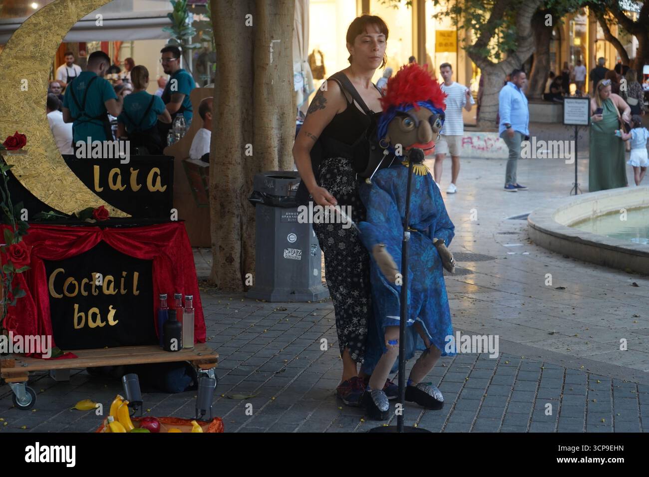 Un ventriloque se produit avec une marionnette dans une rue d'Héraklion. Un bar artisanal, faisant partie du décor du spectacle, ajoute à l'atmosphère artistique. Banque D'Images