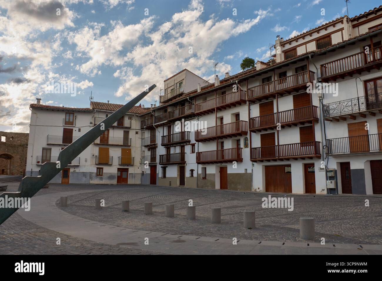 La vibrante place Pla de Estudi à Morella prend vie sous un ciel bleu parsemé de nuages blancs, mettant en valeur un groupe de bâtiments traditionnels Banque D'Images
