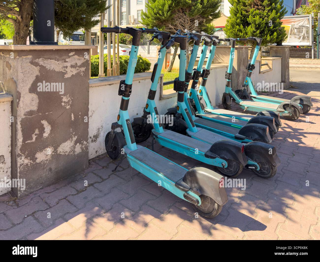 Rangée de scooters électriques partagés garés sur le trottoir urbain à la lumière du soleil Banque D'Images