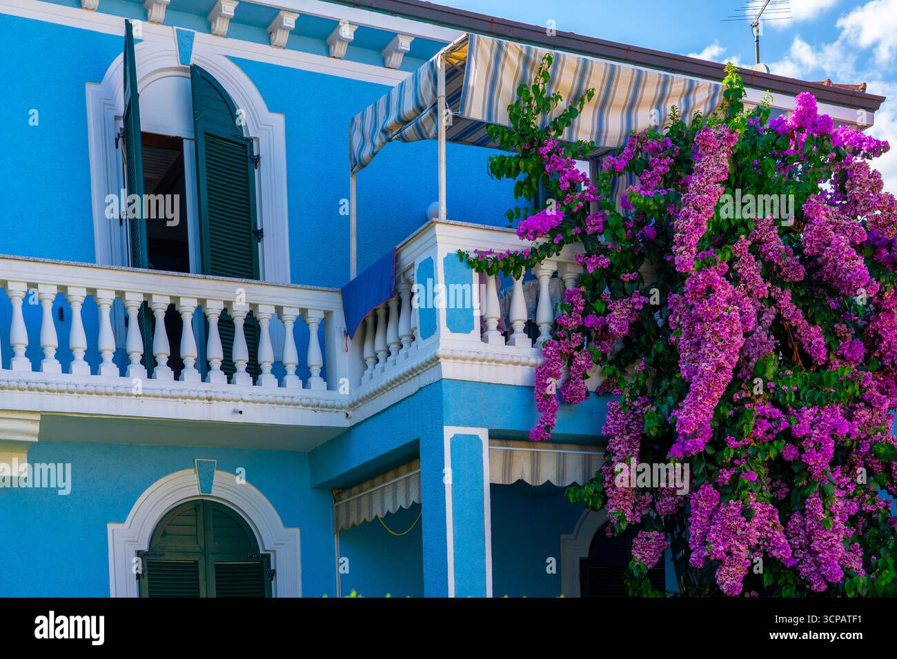 Villa méditerranéenne bleue avec balcon, volets et fleurs de bougainvilléea roses Banque D'Images