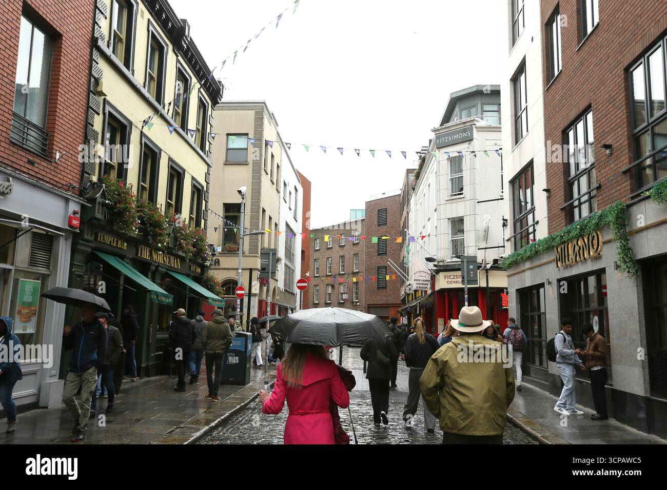 Dublin, Irlande - 19 septembre 2025 - scène de rue de Temple Bar où des personnes avec des parapluies et des imperméables traversent pendant les précipitations dans la ville de Dublin par un après-midi couvert humide dans la capitale irlandaise Banque D'Images