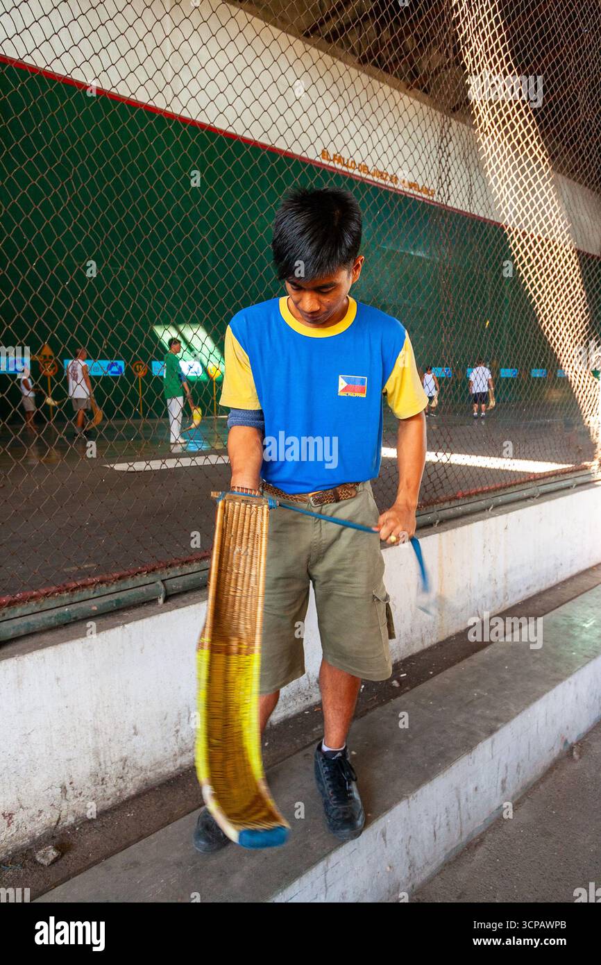 Un jeune pelotari philippin montrant comment enfiler sa cesta à un fronton Jai Alai à Cebu City, Philippines Banque D'Images