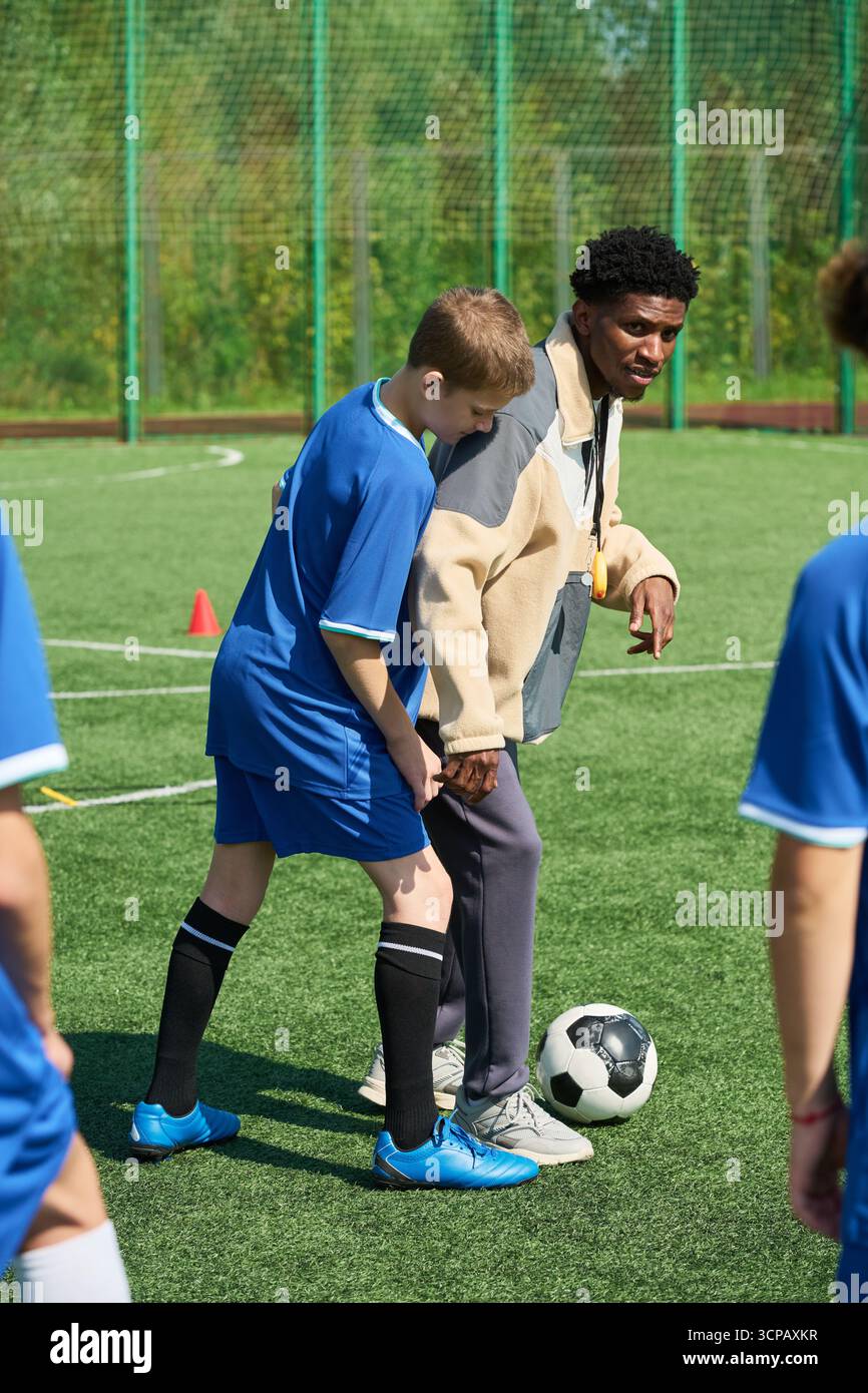 Garçon apprenant les compétences de football de Black Man Coach en plein air Banque D'Images