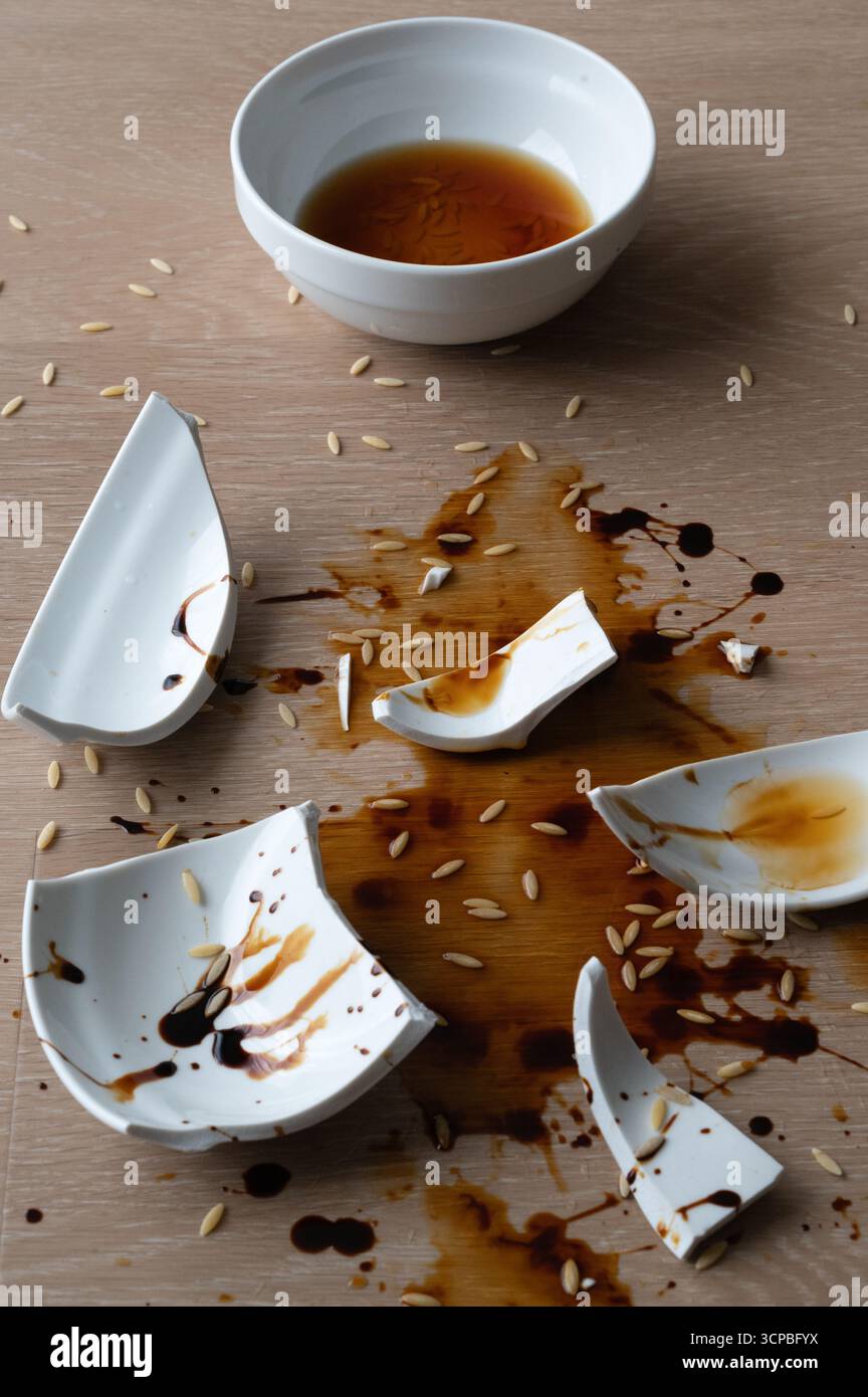 Une représentation créative et artistique d’un bol cassé, avec sauce et riz éparpillés tout autour Banque D'Images