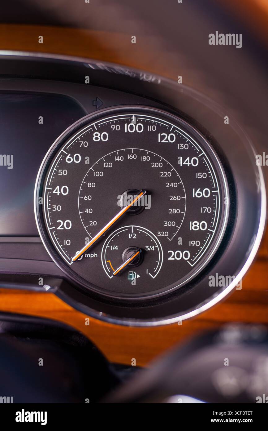 Compteur de vitesse analogique classique affichant des miles et des kilomètres par heure dans une voiture moderne de luxe avec des garnitures chromées et en bois Banque D'Images