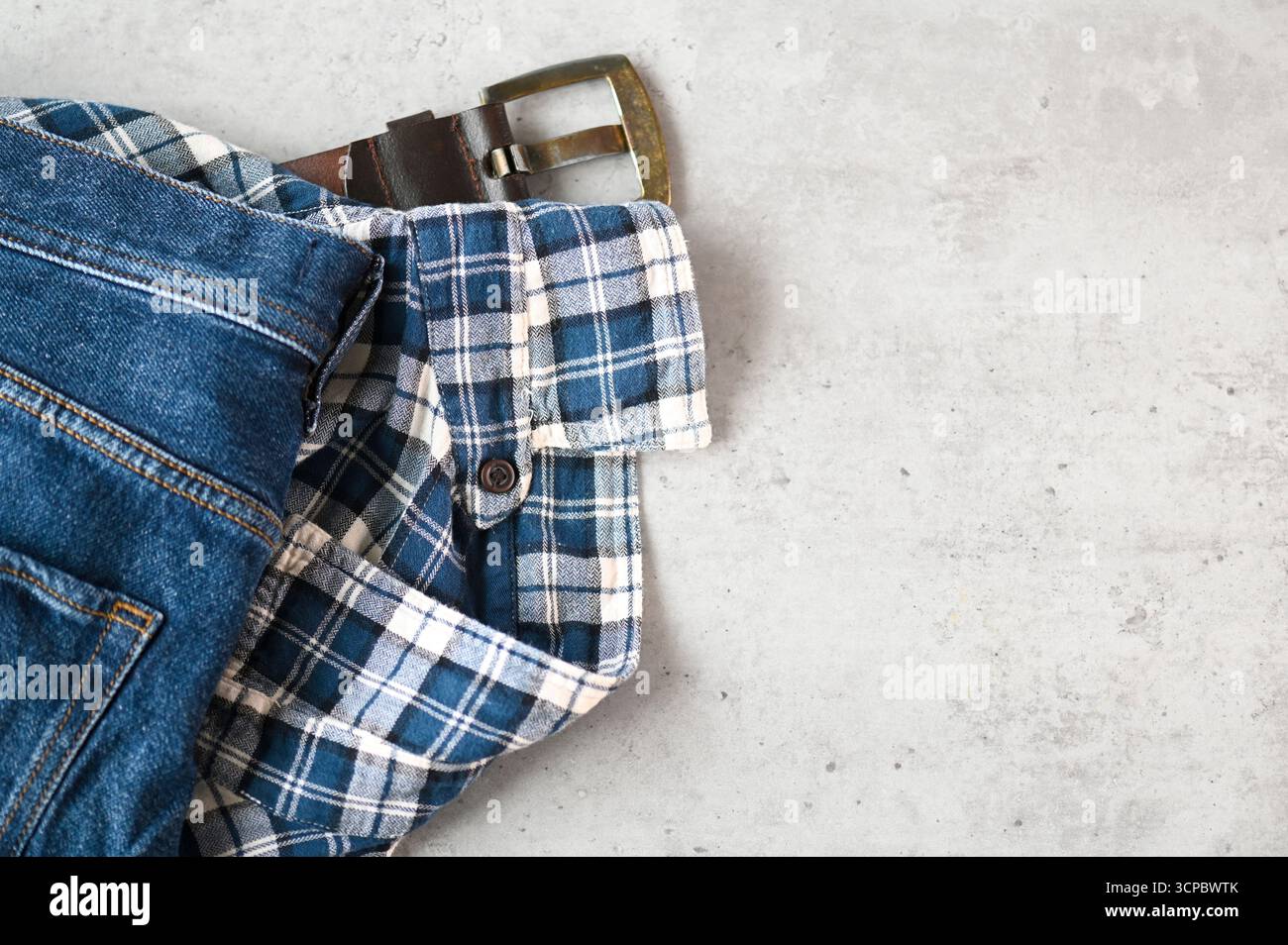 Messy casual Things jeans, chemise et ceinture sur une table, vue de dessus, espace pour le texte Banque D'Images