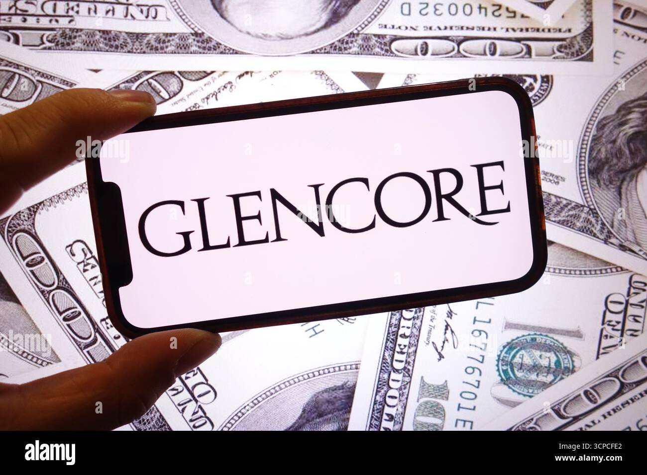 Dans cette illustration photo, le logo de la société Glencore est affiché sur un écran de smartphone avec le billet en dollars américains en arrière-plan. Banque D'Images