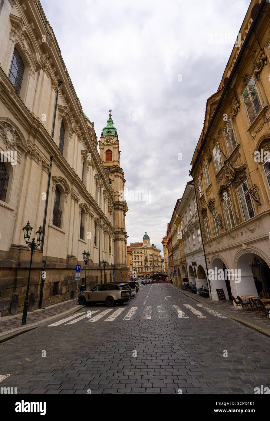 Tour de l'église Saint-Nicolas sur la rue pavée à Prague. Banque D'Images