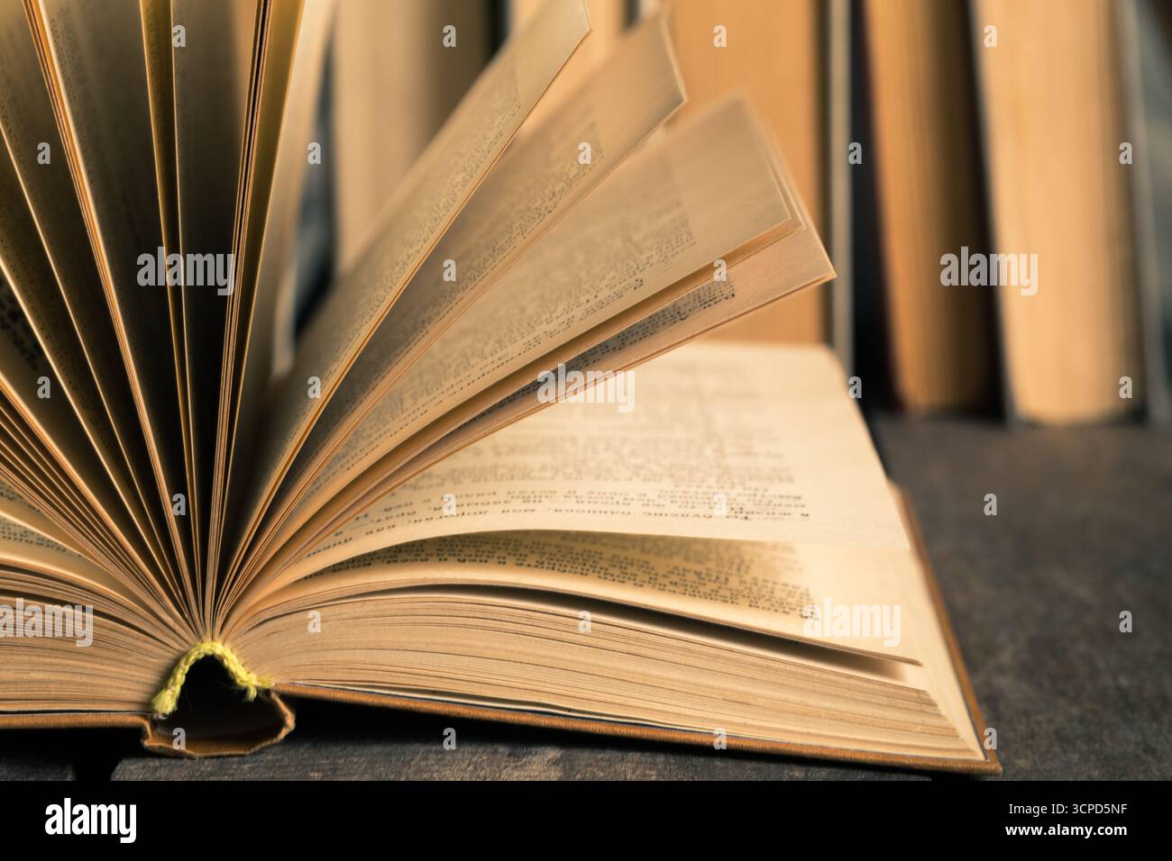 Livre ouvert reposant sur une table avec des étagères de fond remplies de plus de livres Banque D'Images