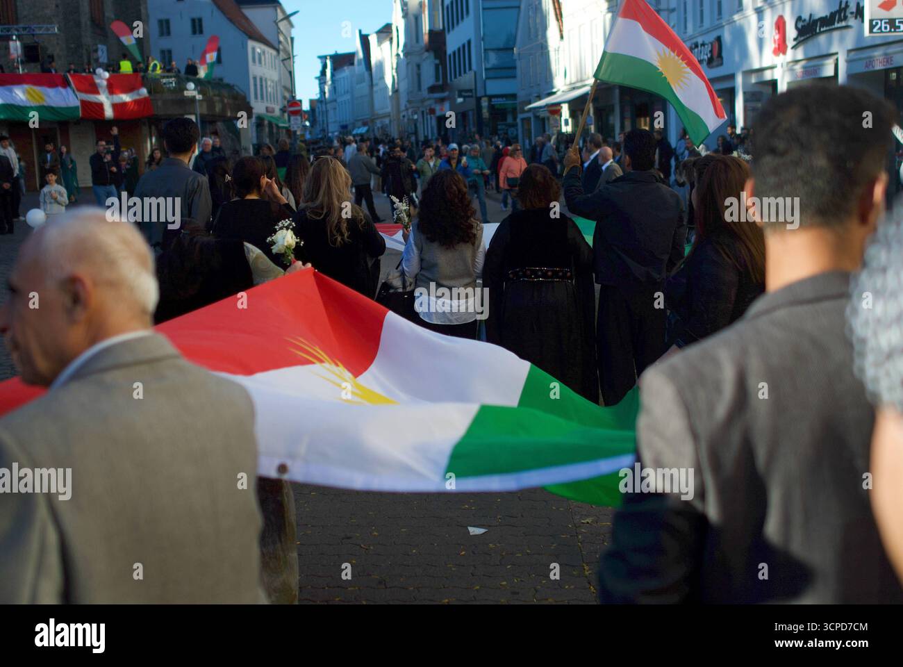 Kurdisches Fest auf dem Südermarkt Flensburg : Gedenken an den 25. Septembre 2017. Frauen und Männer halten eine große kurdische Flagge während eines Festumzugs auf dem Südermarkt in Flensburg. IM Hintergrund zahlreiche Zuschauende und weitere Fahnen. Aufnahme vom 25.09.2025, Flensburg, *** Festival kurde sur le Südermarkt Flensburg commémoration du 25 septembre 2017 femmes et hommes tiennent un grand drapeau kurde lors d'un défilé sur le Südermarkt à Flensburg en arrière-plan de nombreux spectateurs et autres drapeaux photo prise le 25 09 2025, Flensburg, Banque D'Images