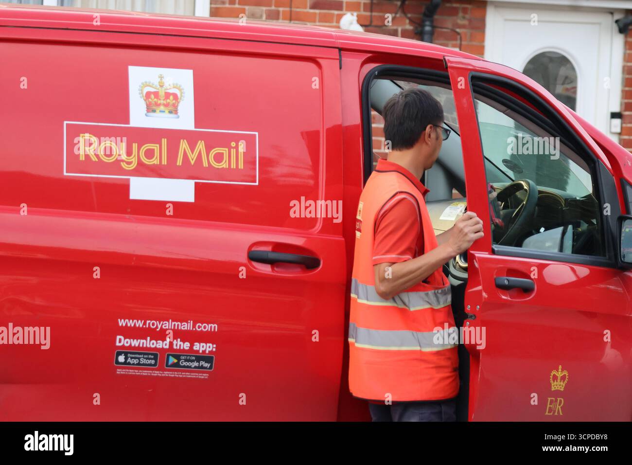 Postier Royal Mail en gilet de sécurité à la porte ouverte d'une camionnette de livraison rouge Banque D'Images