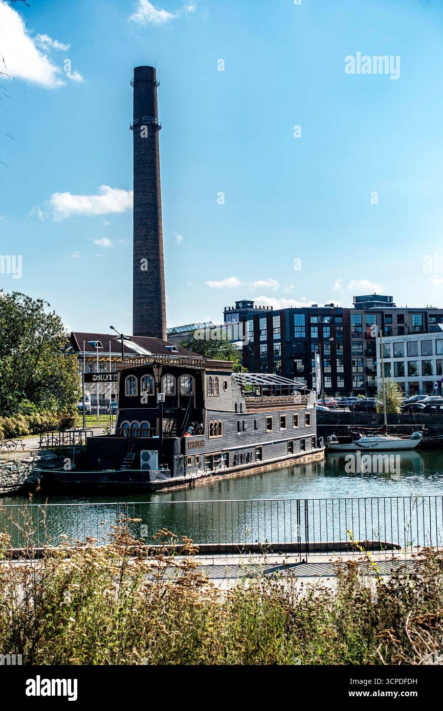 Restaurant en bois en forme de bateau amarré à Tallinn, Estonie, avec une grande cheminée industrielle et des bâtiments modernes en arrière-plan par une journée ensoleillée. Banque D'Images