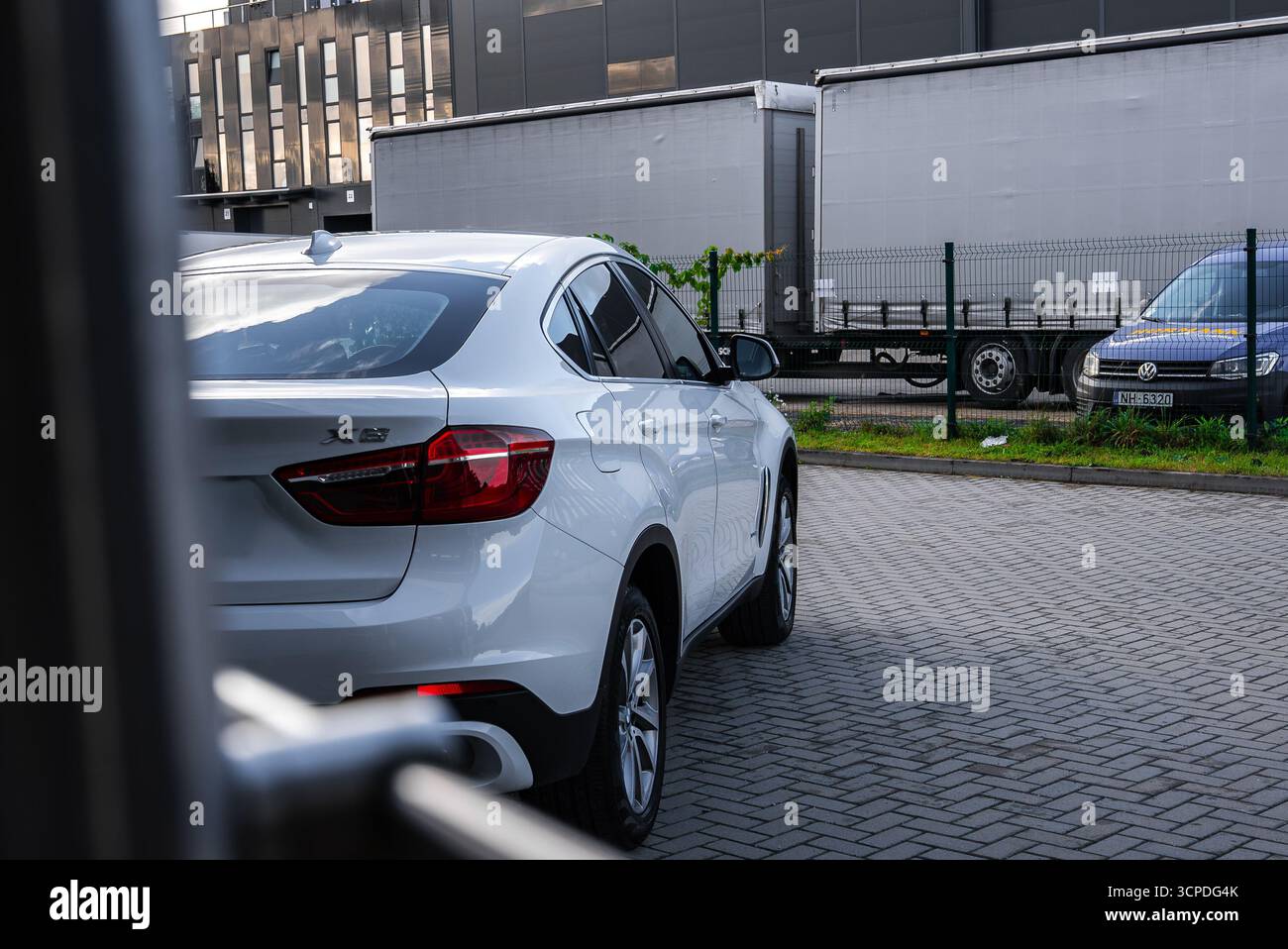 BMW X6 blanche garée près d'un terrain clôturé dans la zone industrielle Banque D'Images