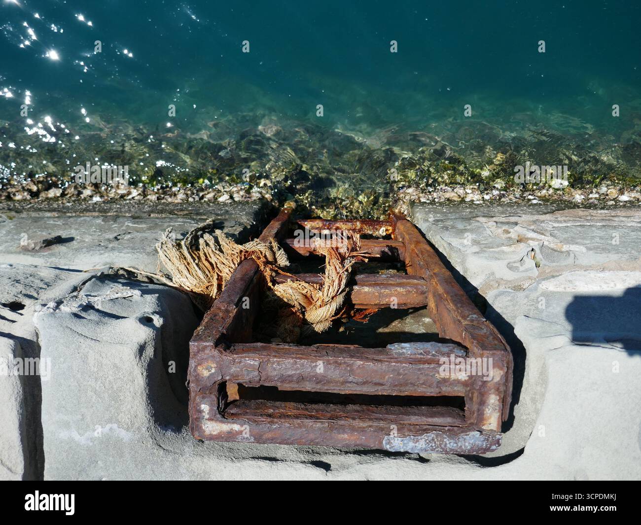 Échelle de secours en métal rouillé sur le mur de mer avec les vagues de l'océan coulant en dessous Banque D'Images