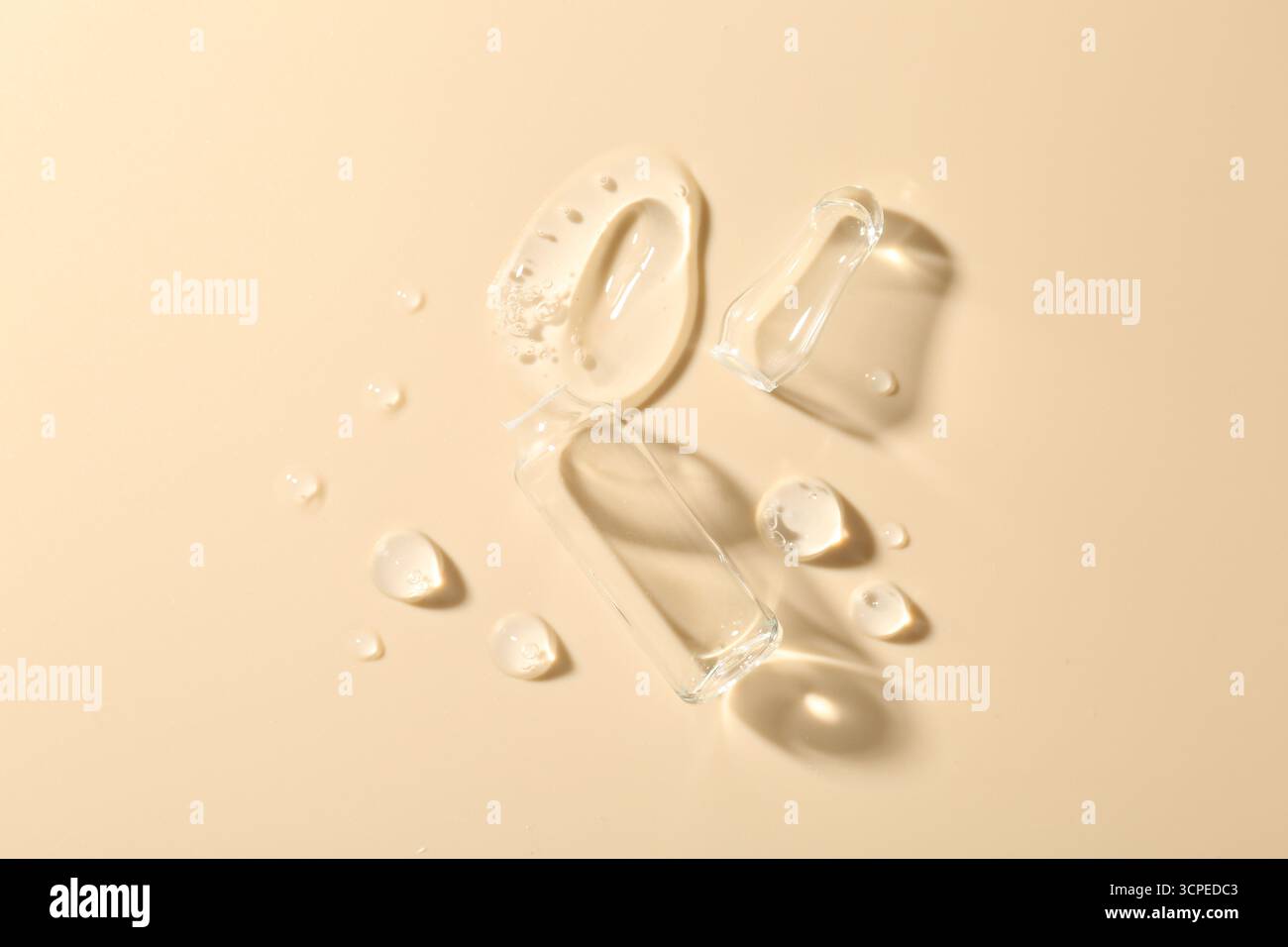 Ampoule en verre cassé et produit cosmétique sur fond beige, vue de dessus Banque D'Images