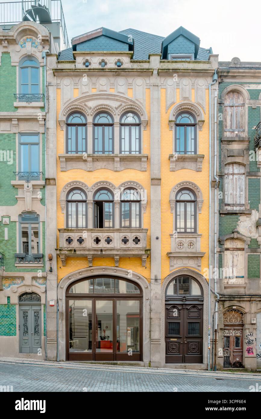 Façade du bâtiment Porto avec murs jaunes, maçonnerie en pierre ornée et fenêtres cintrées symétriques sur une rue pavée. Centre-ville, néo-classique Banque D'Images