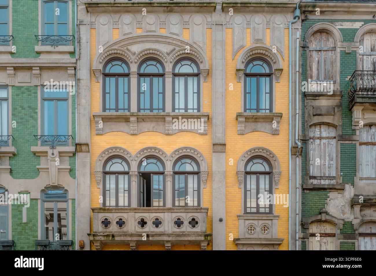 Porto façade de bâtiment avec briques jaunes, fenêtres cintrées symétriques et balcon en pierre orné au Portugal. Scène de rue du centre-ville, néo-classique Banque D'Images