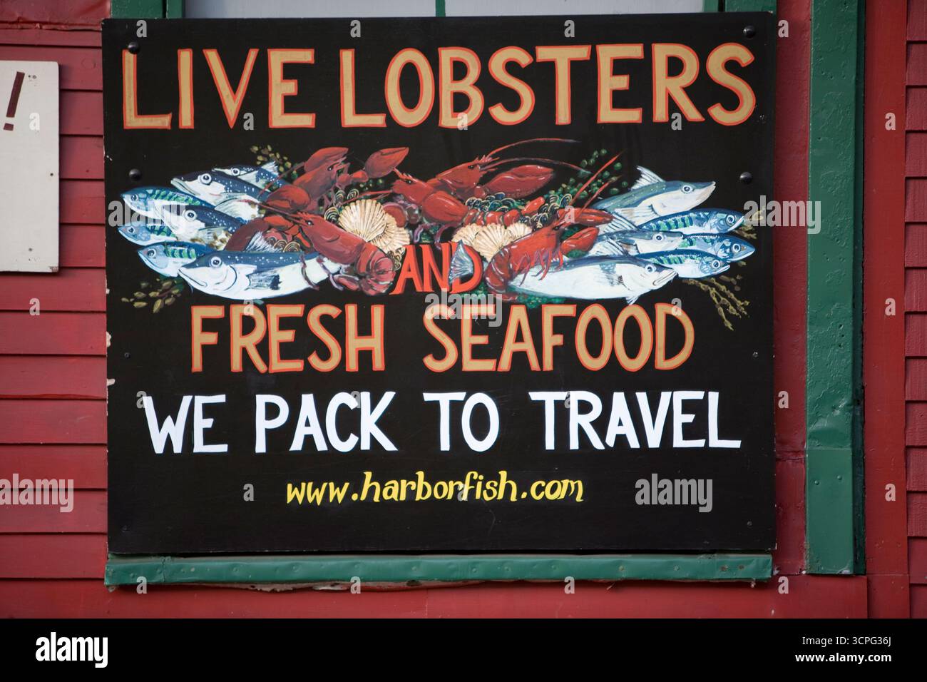 Un panneau coloré faisant la publicité de homards vivants et de fruits de mer frais est accroché sur un mur de bois rouge à Portland, ME. Banque D'Images