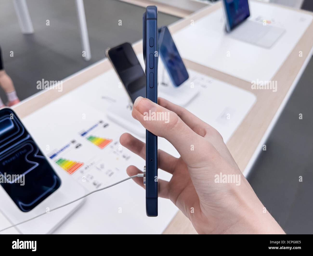Poznan, Pologne - 20 septembre 2025 : iPhone 17 Pro, un smartphone bleu, est tenu par la main d'un client, mettant en valeur son design dans un commerce de détail moderne occupé Banque D'Images