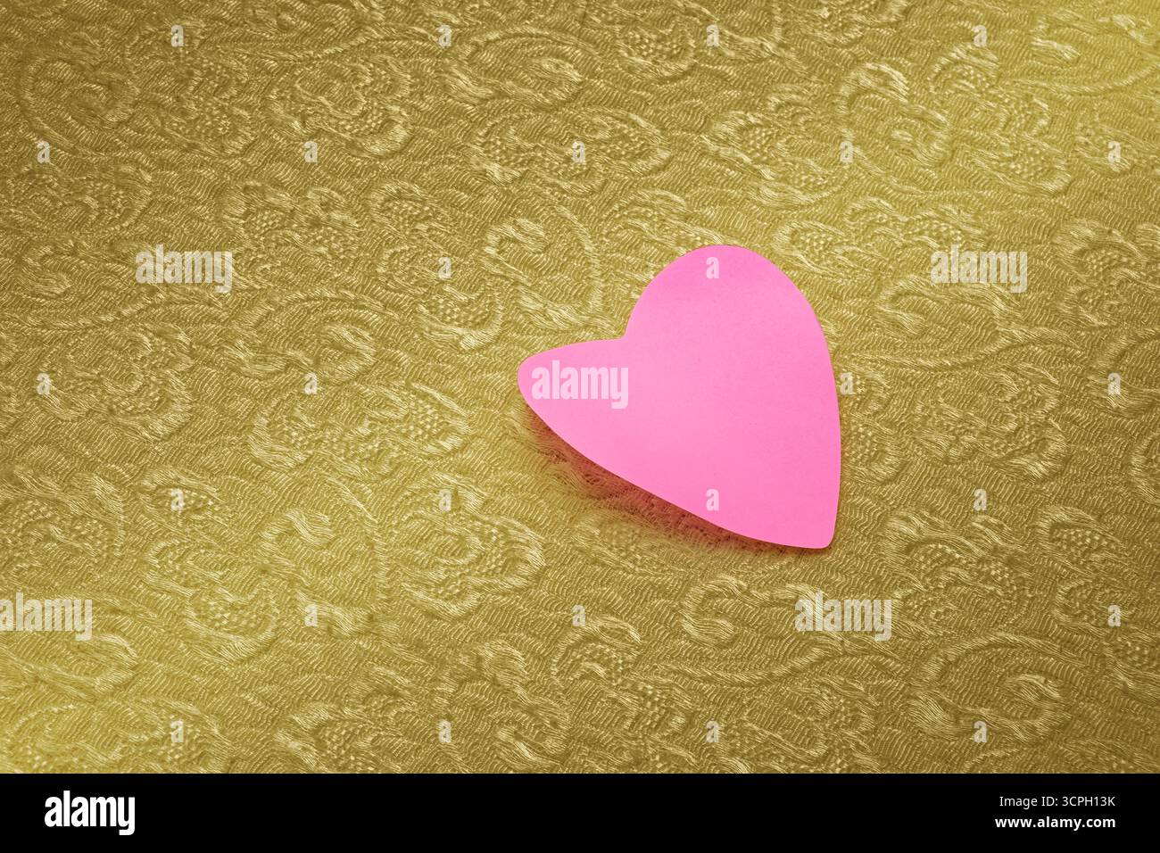 Papier rose coupé en forme de coeur. Sur tissu tissé à motifs. Photo concept de la Saint-Valentin. Banque D'Images