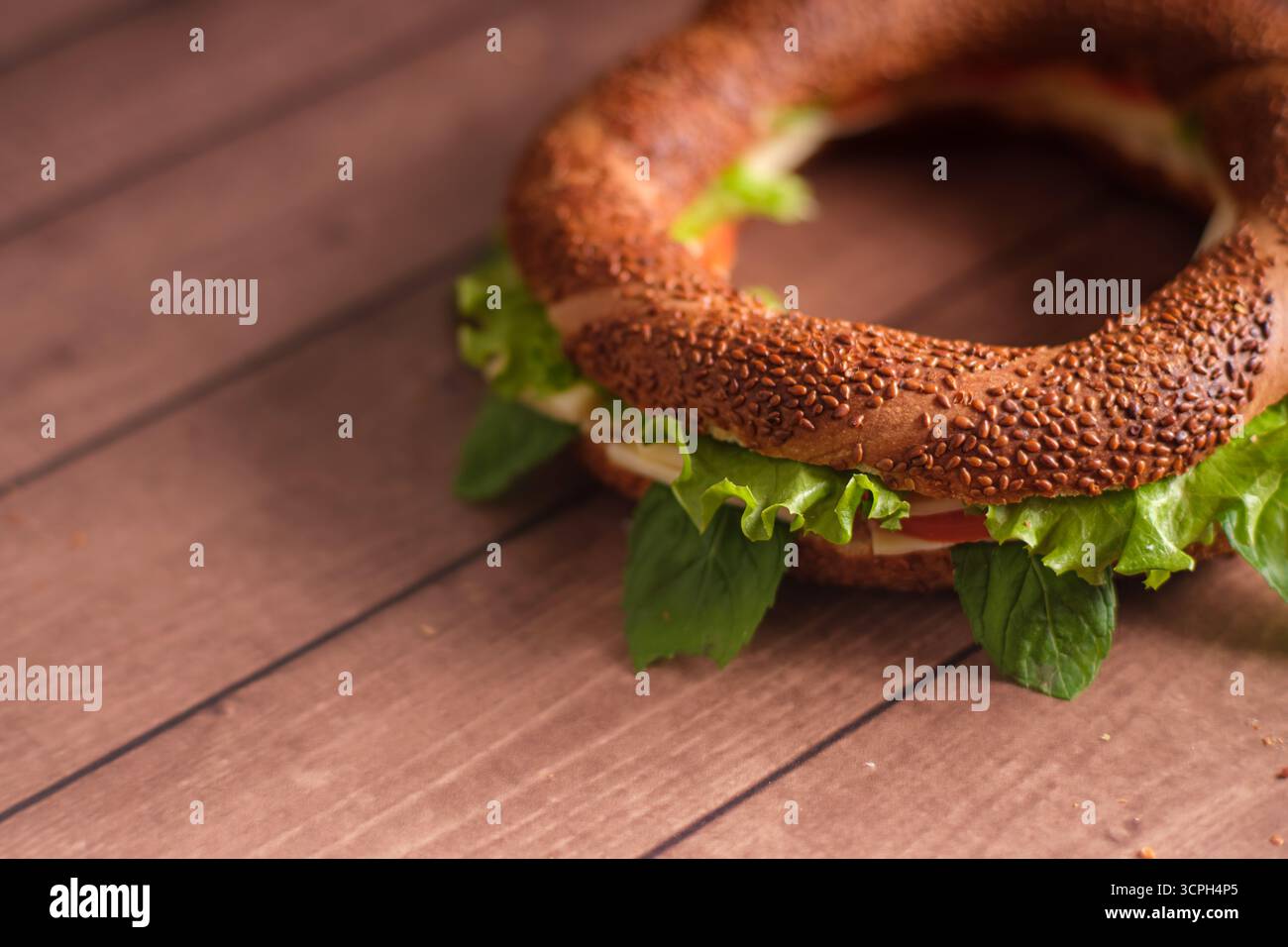Un délicieux sandwich bagel orné de légumes frais, avec des légumes verts et des tomates éclatants. Cette délicatesse appétissante est parfaite pour le petit déjeuner ou Banque D'Images