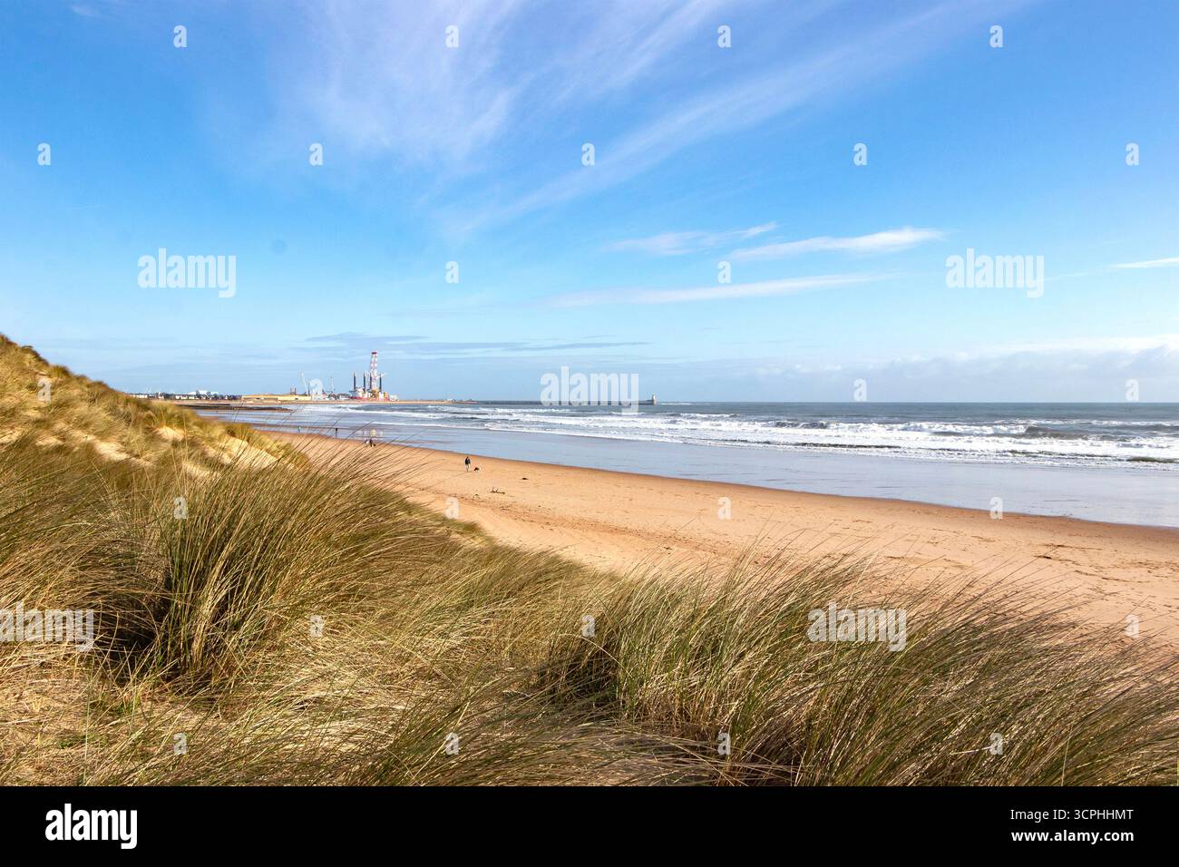Paysage côtier du northumberland avec des dunes de sable doré et de l'herbe de mer, Blyth lointain amarre le port de construction navale par une journée ensoleillée avec un ciel bleu clair Banque D'Images