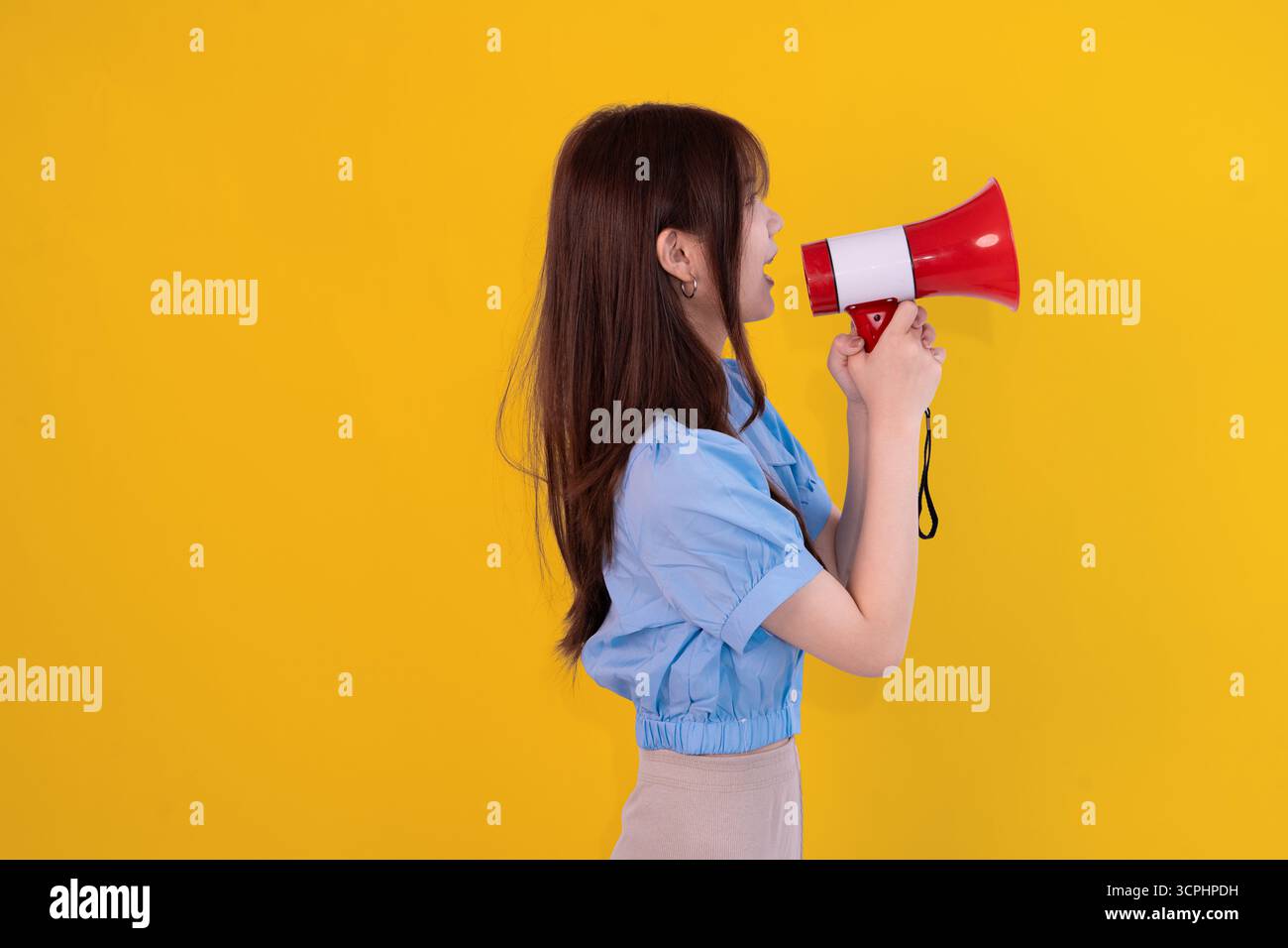 femme criant à travers le mégaphone sur fond jaune audacieux, exprimant l'énergie et l'annonce Banque D'Images