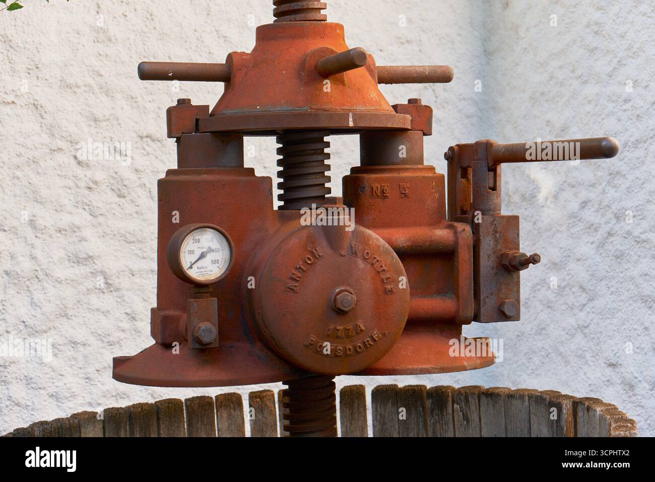 Vue détaillée d'un pressoir à vin antique rouillé dans un tonneau en bois avec des roues en métal vert. Outil de vinification classique et historique, photographié en extérieur aga Banque D'Images