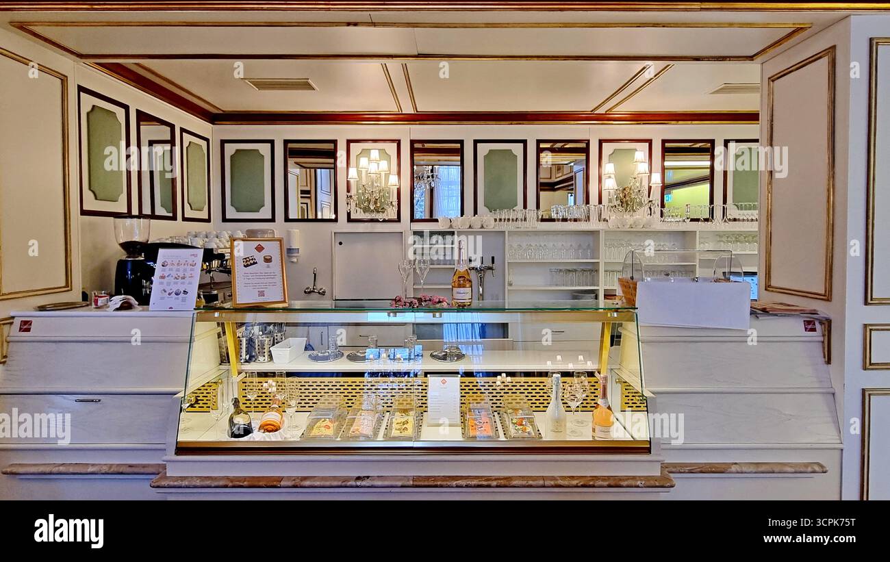 Une vitrine en verre avec des bonbons et des bouteilles de vin mousseux à l'intérieur d'un élégant café-confiserie Banque D'Images