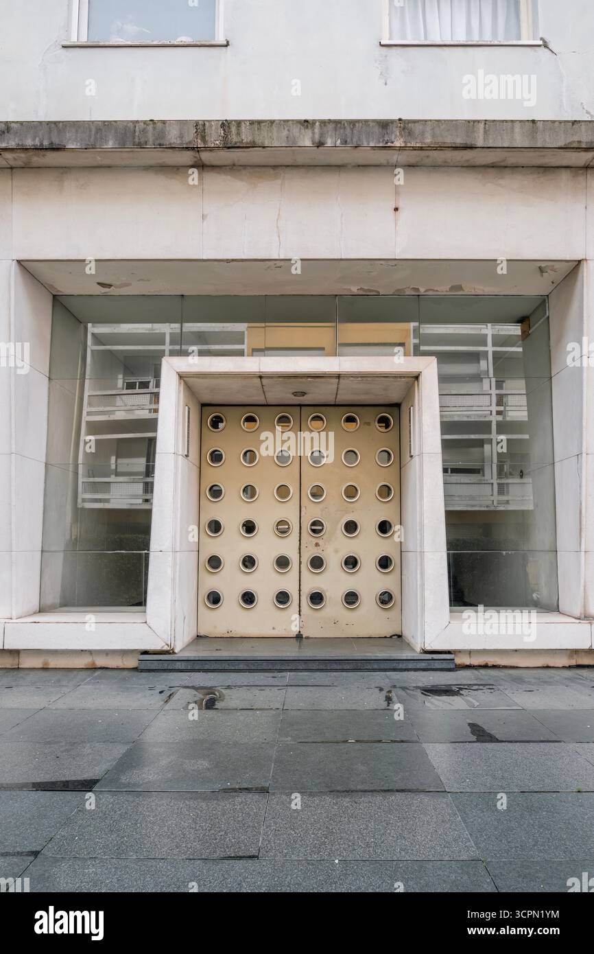 Porte moderniste frappante avec fenêtres circulaires et béton brutaliste sur Une façade de bâtiment public. Architecture abstraite, géométrique, entrée urbaine Banque D'Images