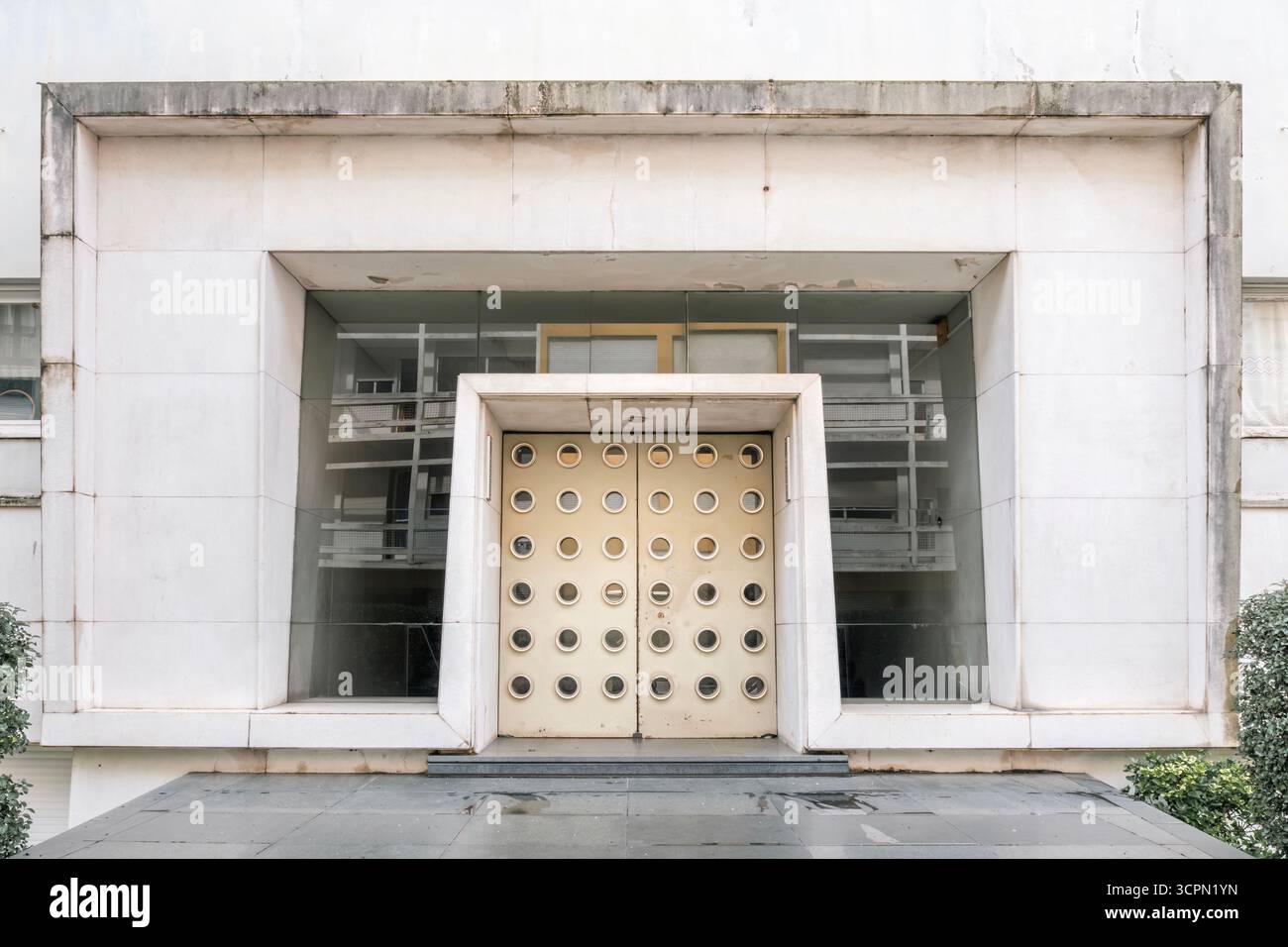 Entrée moderniste avec une paire de portes aux formes circulaires multiples, encadrées par des détails minimalistes en béton. Capture la symétrie géométrique Banque D'Images