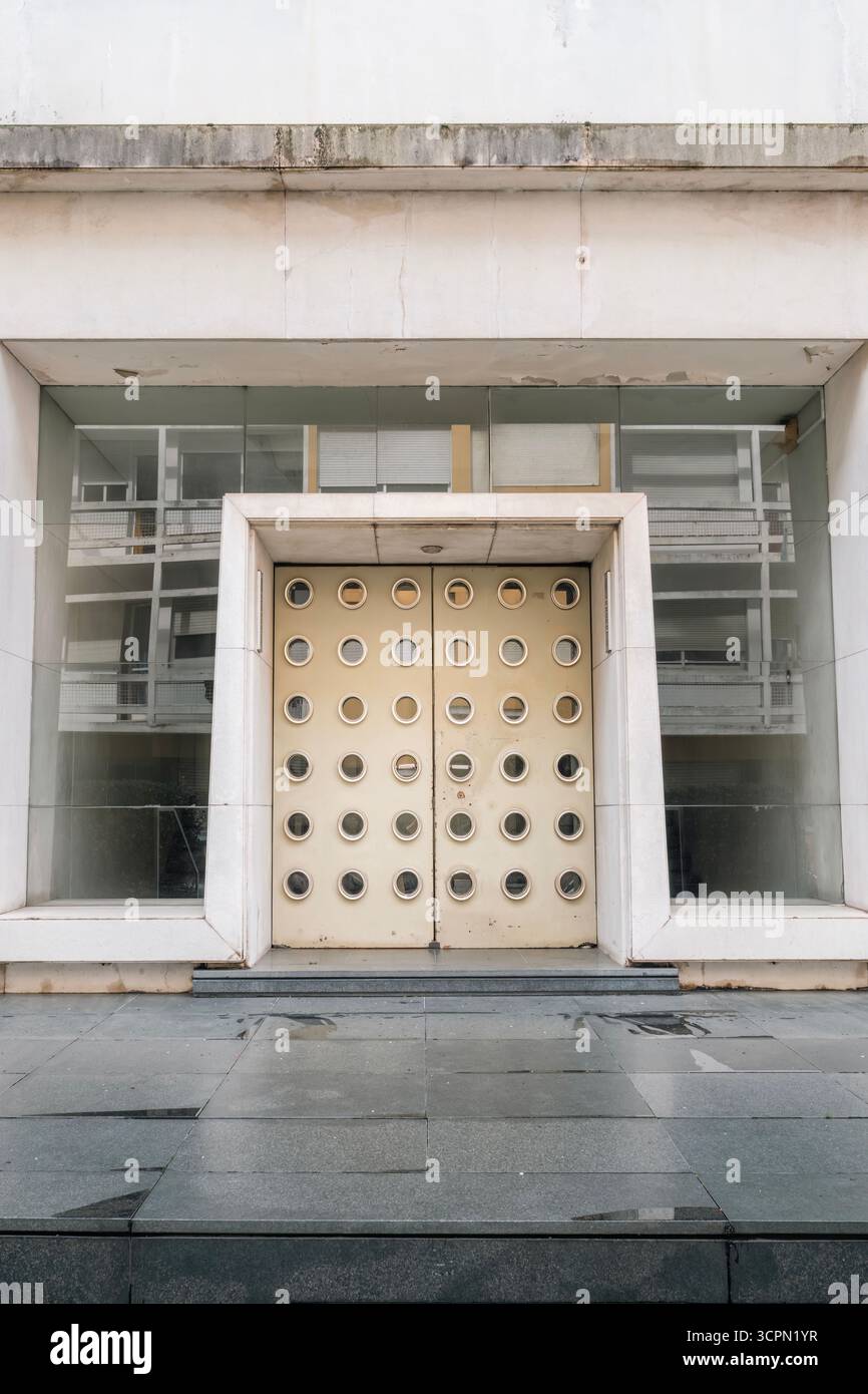 Porte moderniste frappante avec fenêtres de forme circulaire et béton brutaliste sur Une façade de bâtiment public. Architecture abstraite, géométrique, entrée Banque D'Images