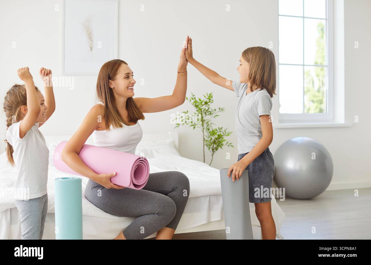Famille joyeux fitness à la maison, la mère yogi et les enfants sportifs donnant haut cinq dans l'excitation, heureux Banque D'Images