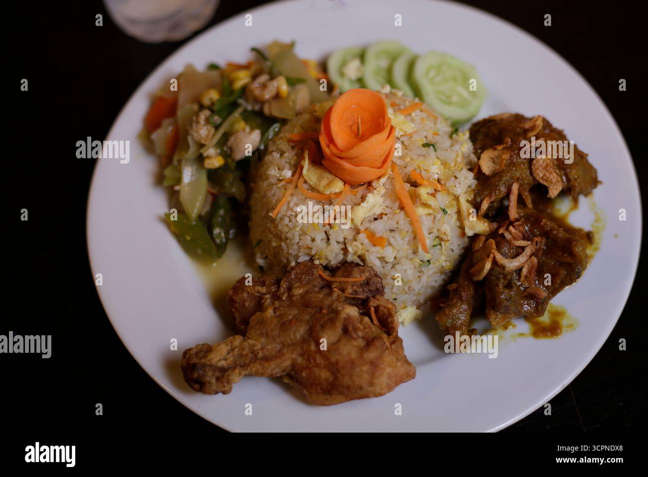 Repas traditionnel de riz frit d'Asie du Sud-est (Nasi Goreng) avec poulet frit et légumes sautés Banque D'Images